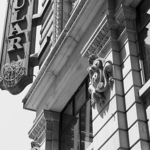 Black and white image of building exterior with sign that reads 